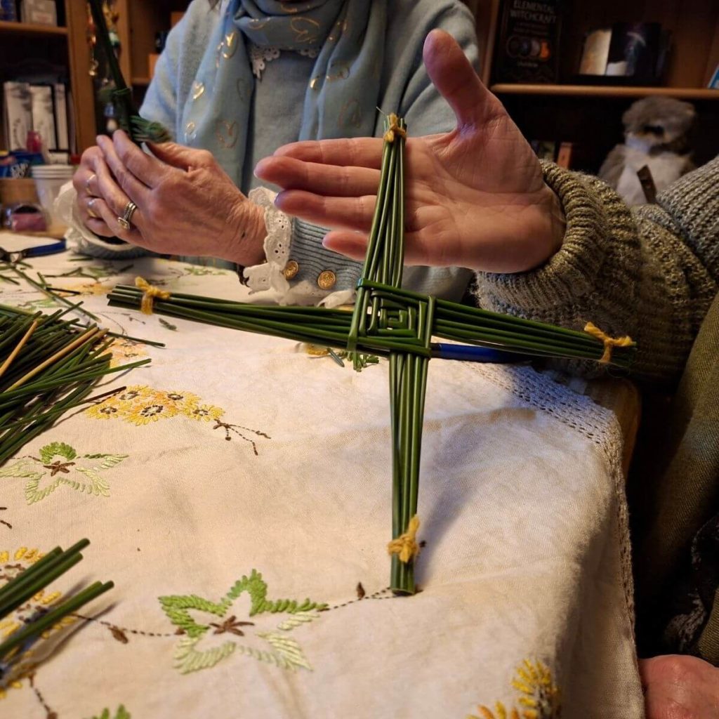 women sitting round a table making st brigids crosses from foraged rushes